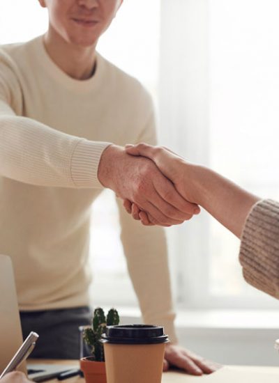 Two people shaking hands across from each other.