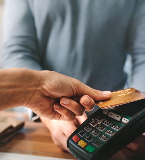 Person in the middle of a contactless payment transaction at a cash register.